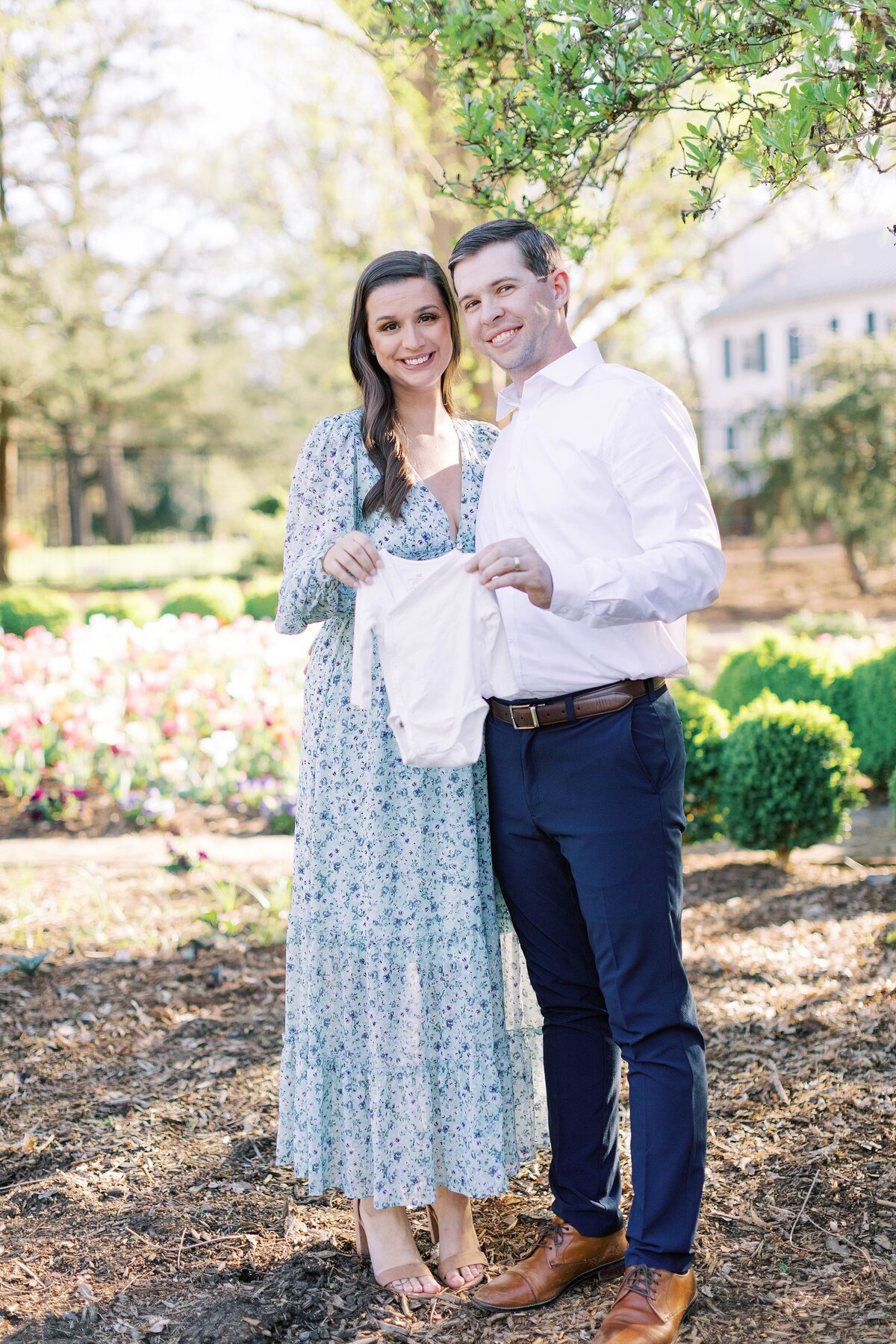 mom and dad holding a onesie for baby