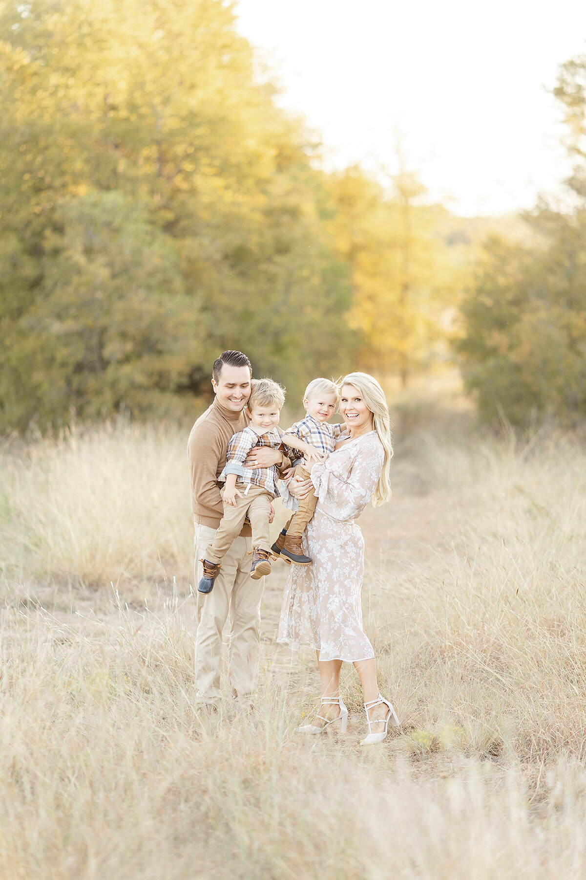 A beautiful DFW family standing by a grassy path posing for their family pictures.