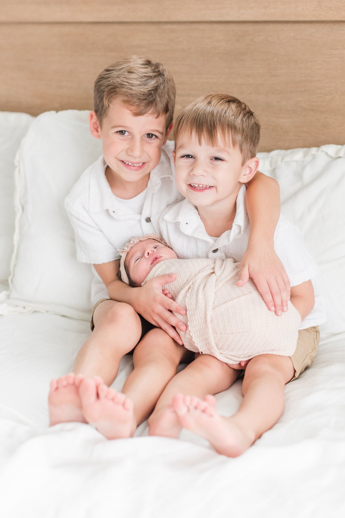 toddler boys holding baby sister in their arms