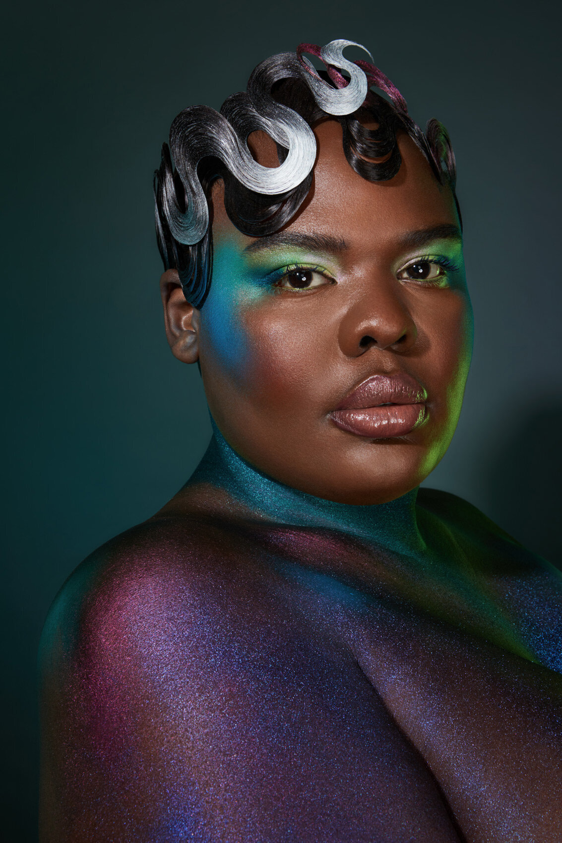 Striking portrait of Gia with glittering skin and bold, colorful makeup, captured by Ylva Erevall.