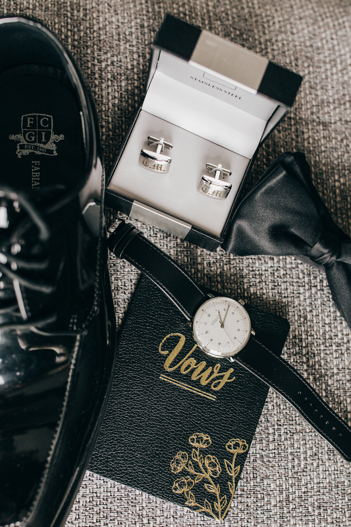Detail shot of groom's wedding vows, watch, cuff links and bow tie