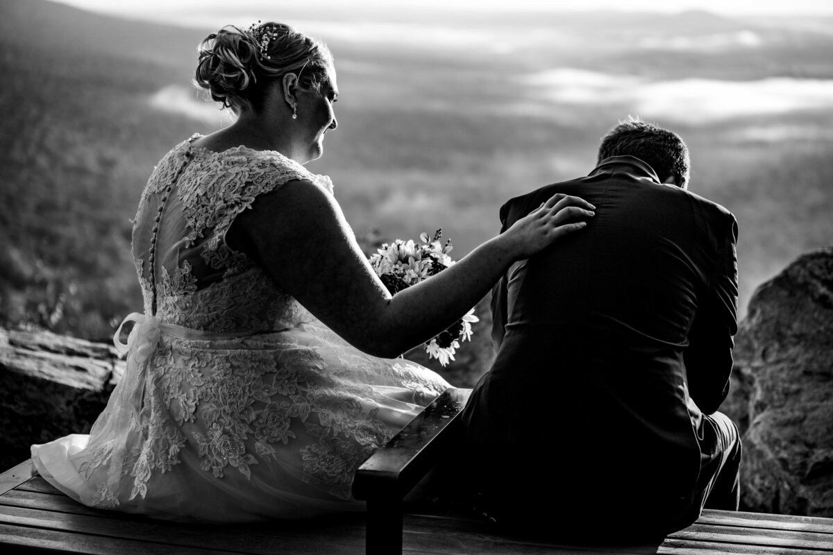 The bride, wearing a beautiful white wedding gown, sits with her groom after a beautiful sunrise first look