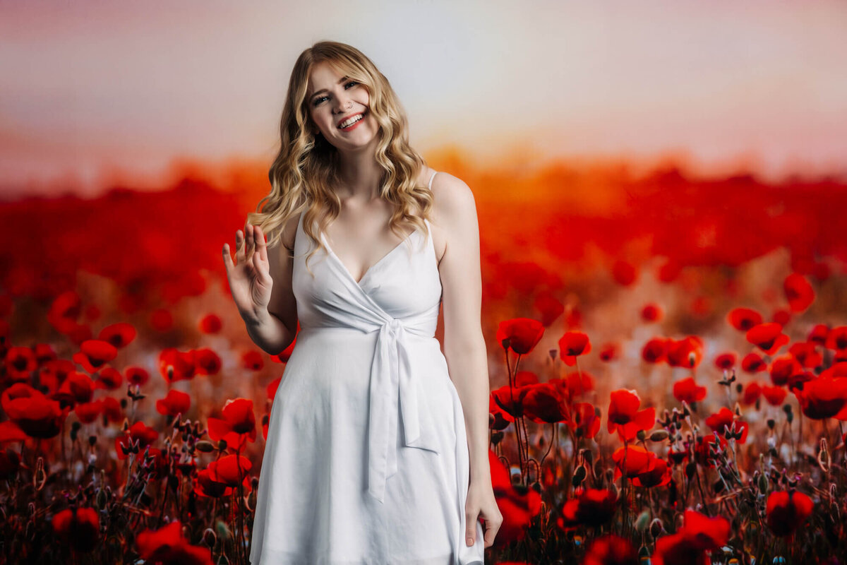 Girl poses in red flower field in Prescott senior photography studio