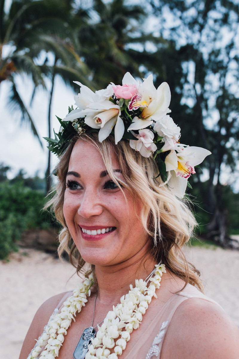 Bride with haku lei and pikake lei smiling after she elopes on the North Shore
