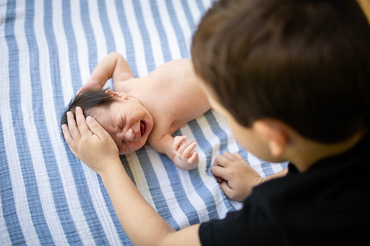 Big brother trying to calm down his newborn baby brothr