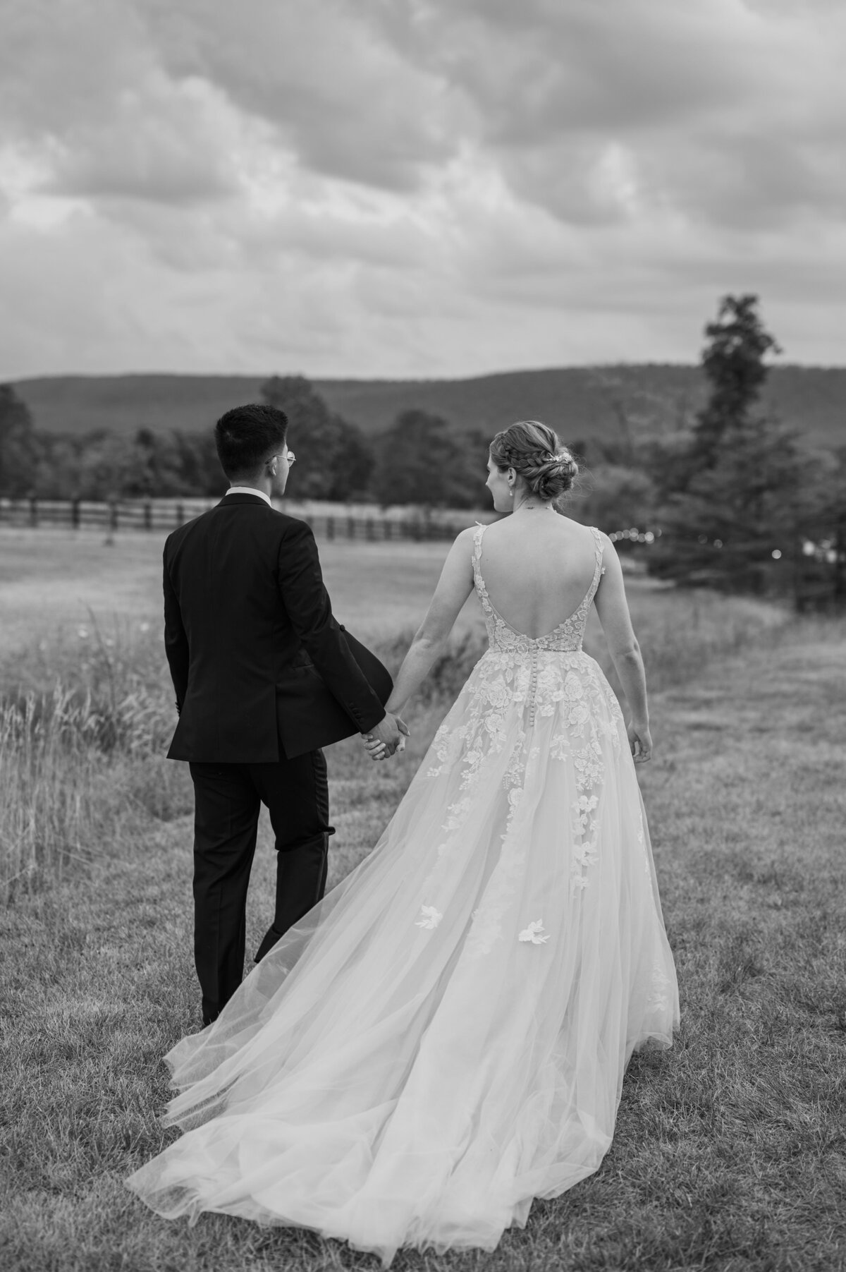 A wedding couple holding hands and walking together in a field