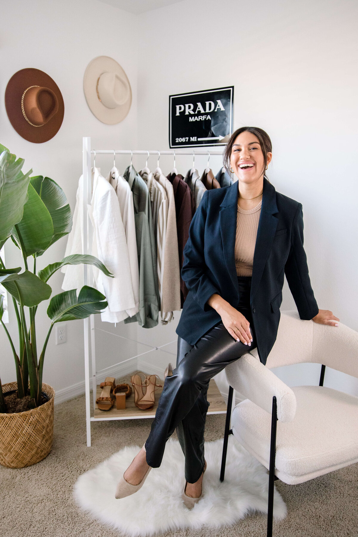 commercial photographers captures clothing brand photoshoot ideas with personal stylist posing in a studio session with woman posing on a chair in front of a sample closet for a client