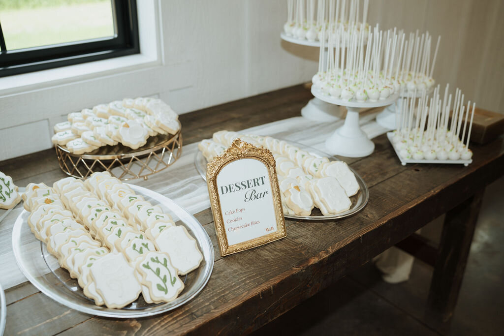 wedding dessert bar sign in gold antique frame on rustic table with dessert options