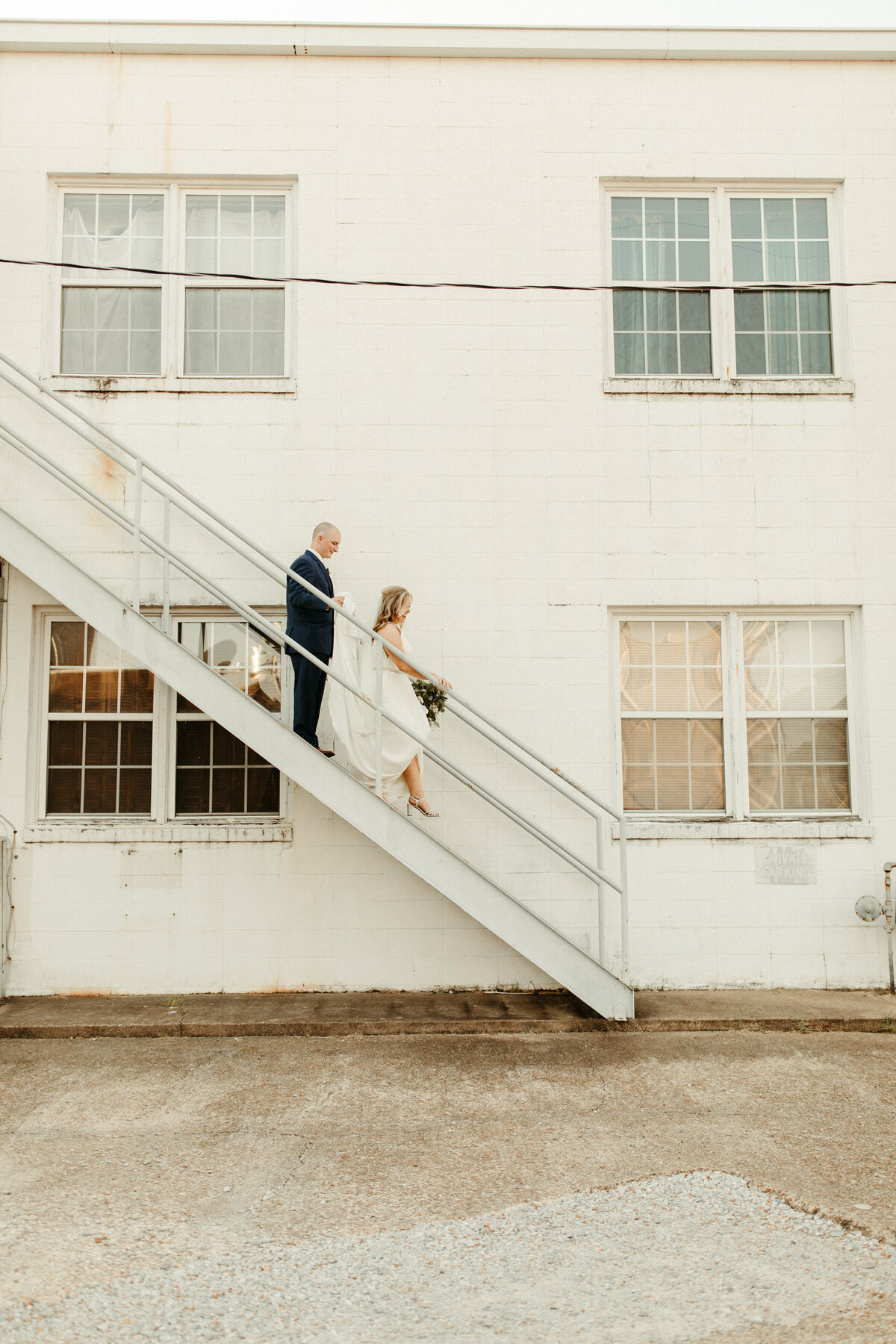 Bride and groom walking down staircase against a building downtown