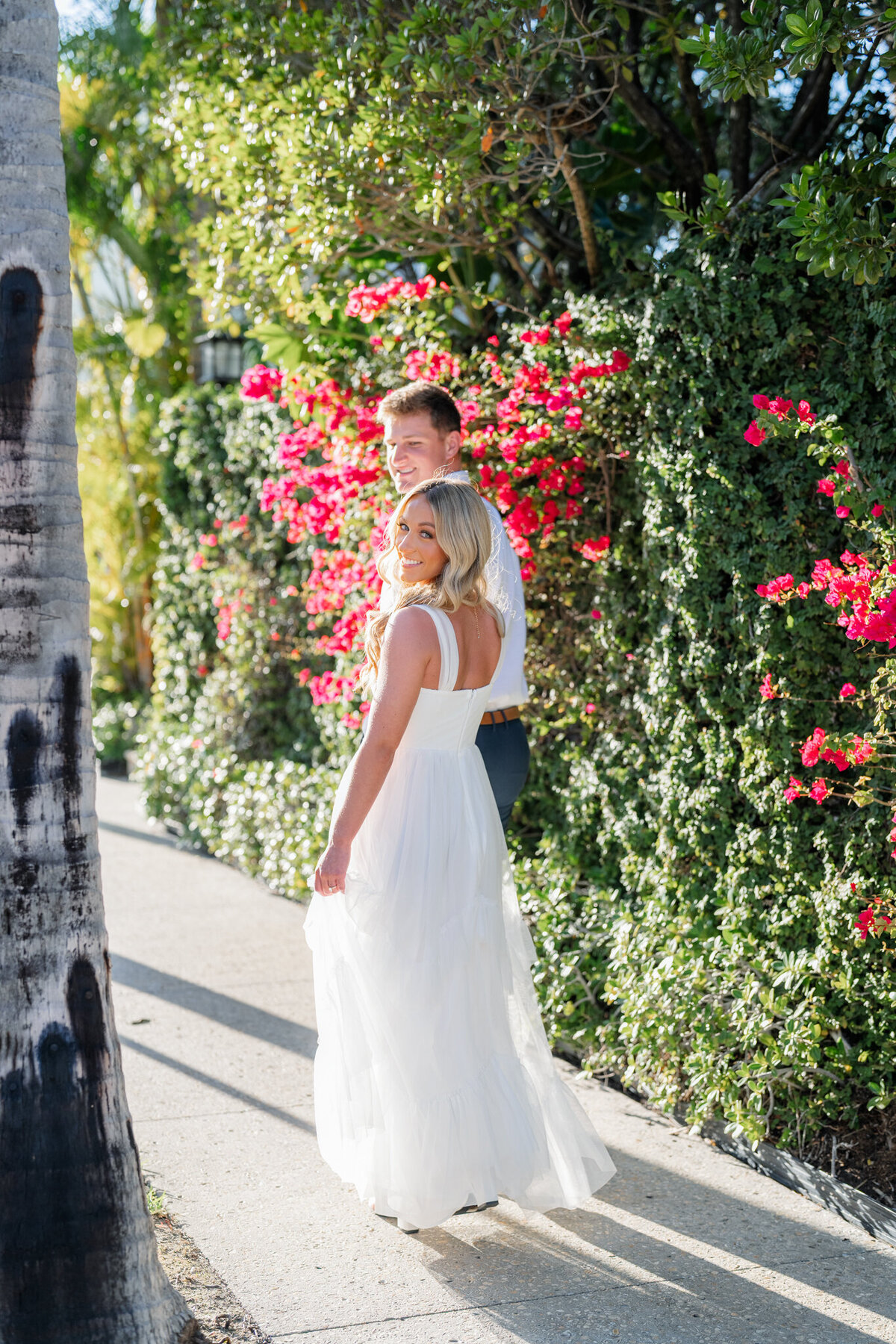 Couple smiling and walking next to vibrant florals and greenery