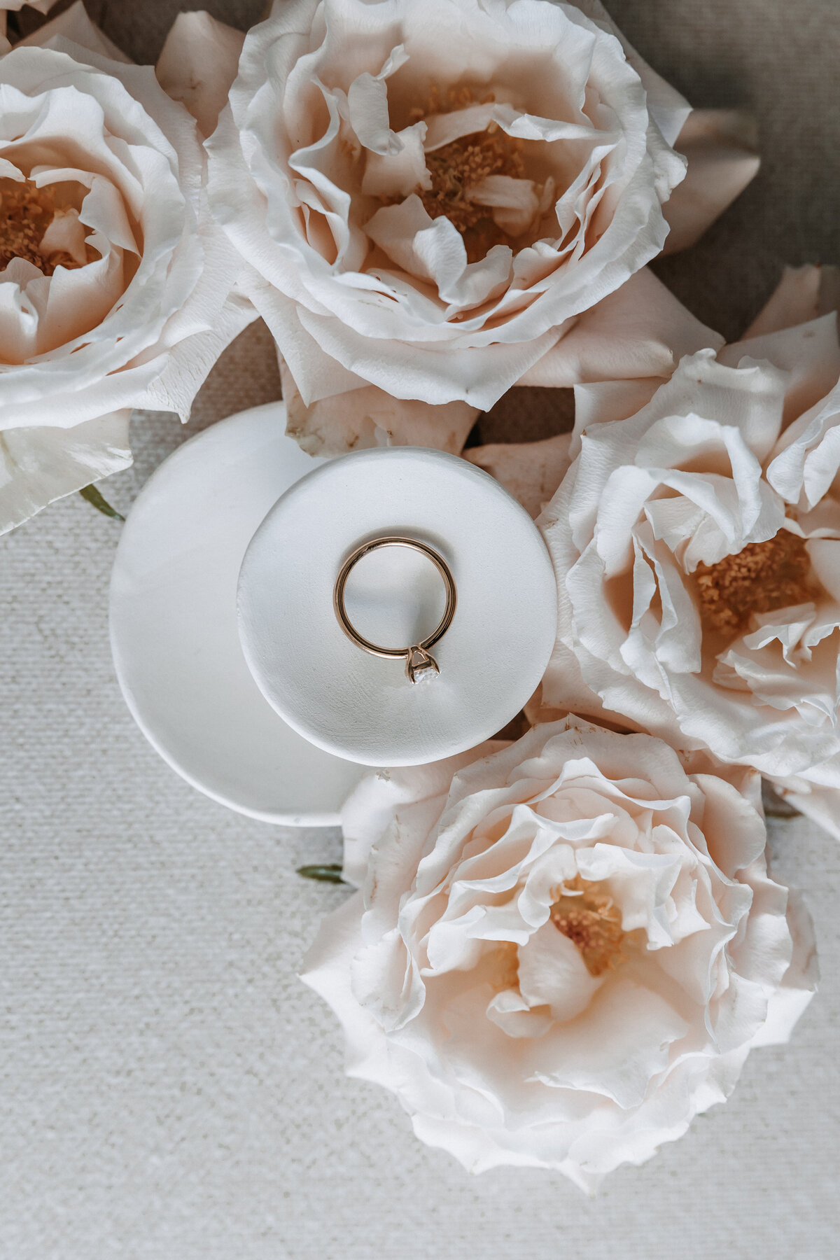 flat lay detail photo of wedding ring surrounded by pink flowers