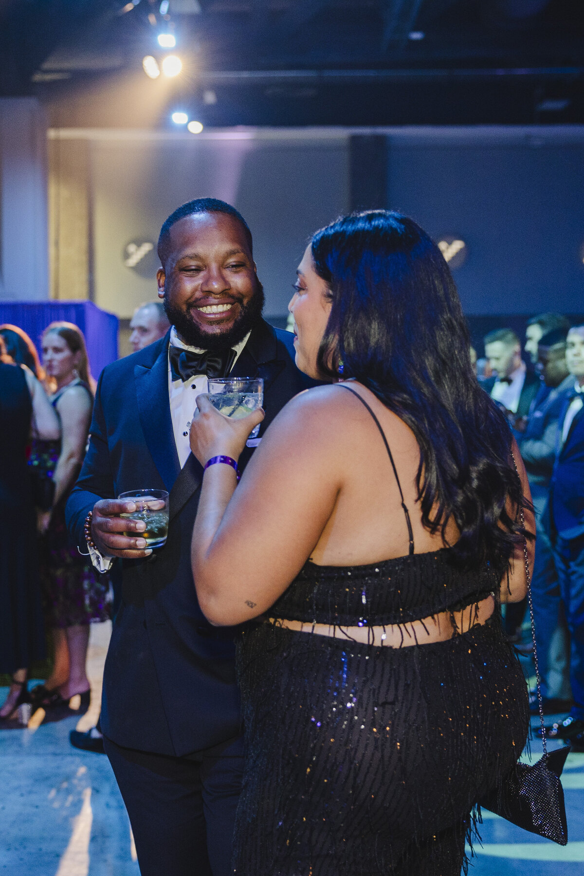 Two people chat while holding drinks.