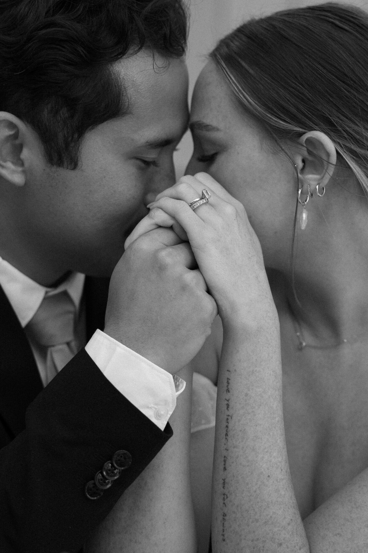 Intimate close-up of the bride and groom's hands intertwined, highlighting their wedding bands in La Jolla in San Diego, California.
