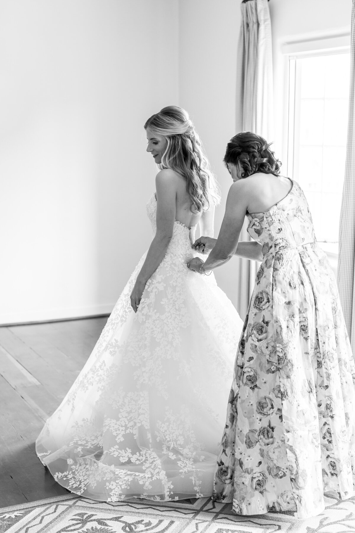 Bridesmaid helping zip up bride