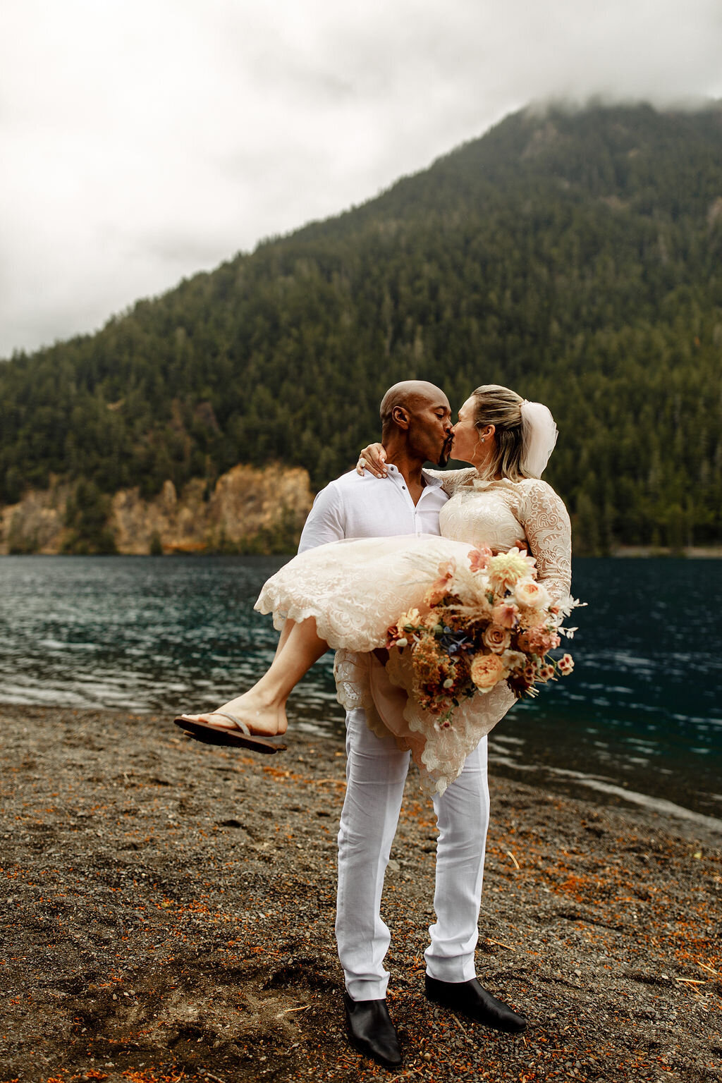 Groom carrying and kissing bride after elopement on Lake Crescent in Olympic National Park!