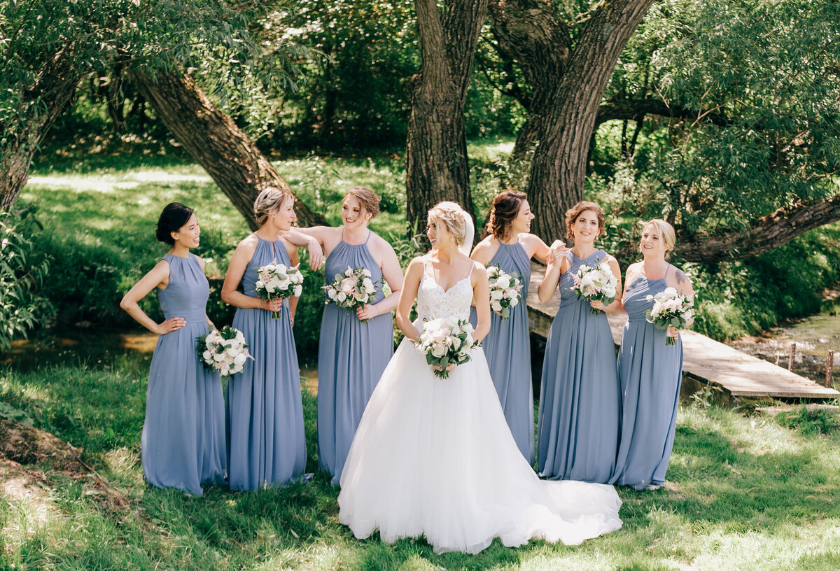 Luxurious outdoor wedding portraits of bride and bridesmaids in light blue dresses