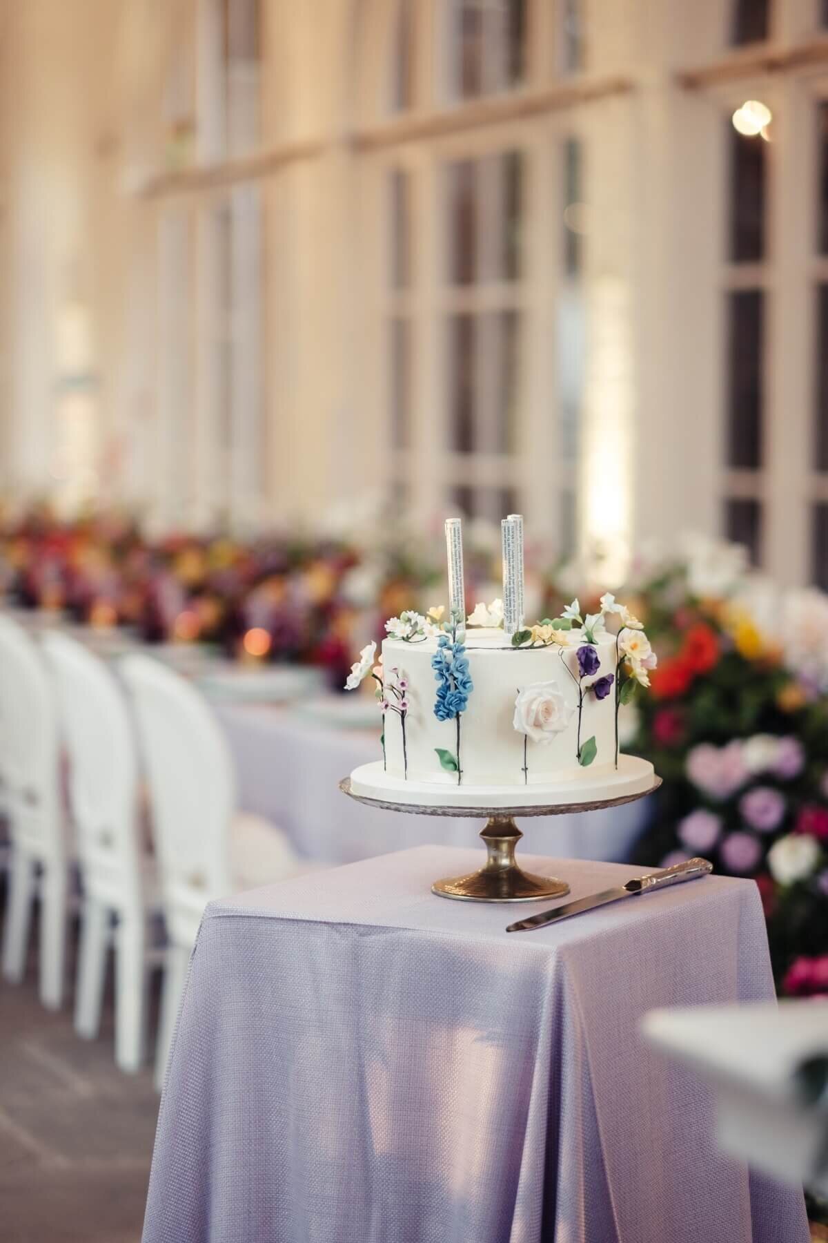 A cake with hand painted flower stems on the sides and sugar flowers coming from the stems on the side of the cake