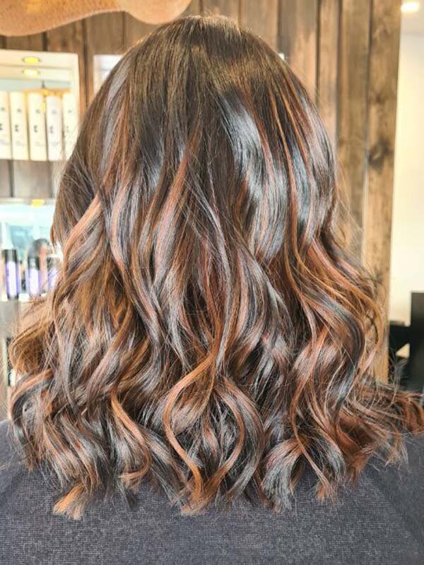Rich brunette hair with caramel highlights styled in soft waves, showcasing expert colour correction services at Blake & Kwan Hairdressers.