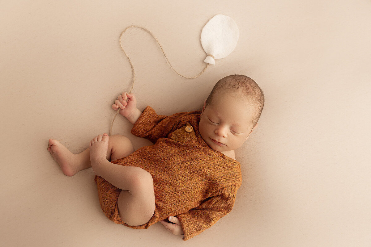 baby boy posed, holding a balloon for his hamilton newborn photoshoot