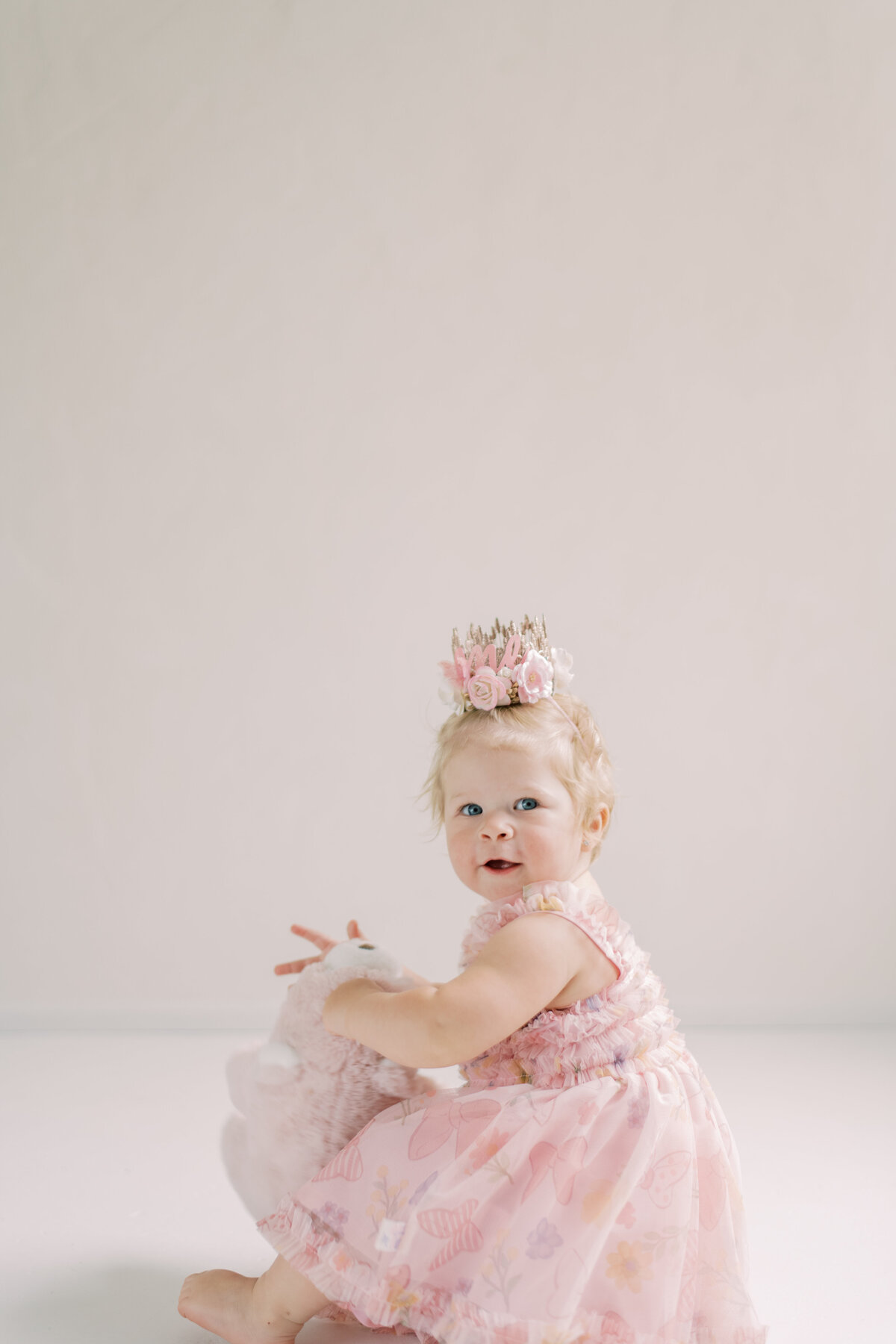 Seated baby with soft pink tulle dress looking up sweetly in natural light