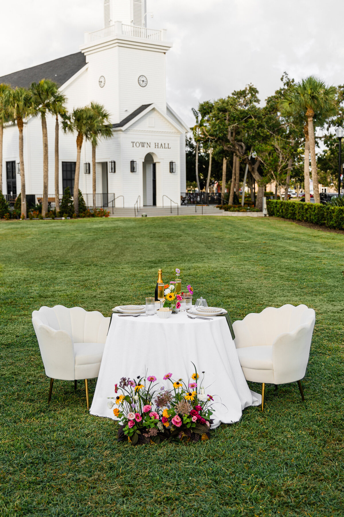 elopement table set up of white and beige with wildflowers in front of farmhouse styled town hall