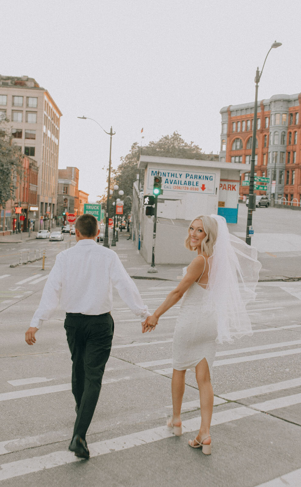 Couple crossing the street while bride looks back over her shoulder
