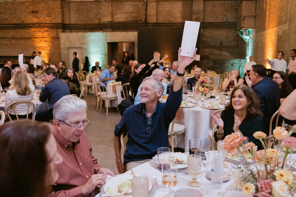 corporate dinner guest holding up winning guess on paper