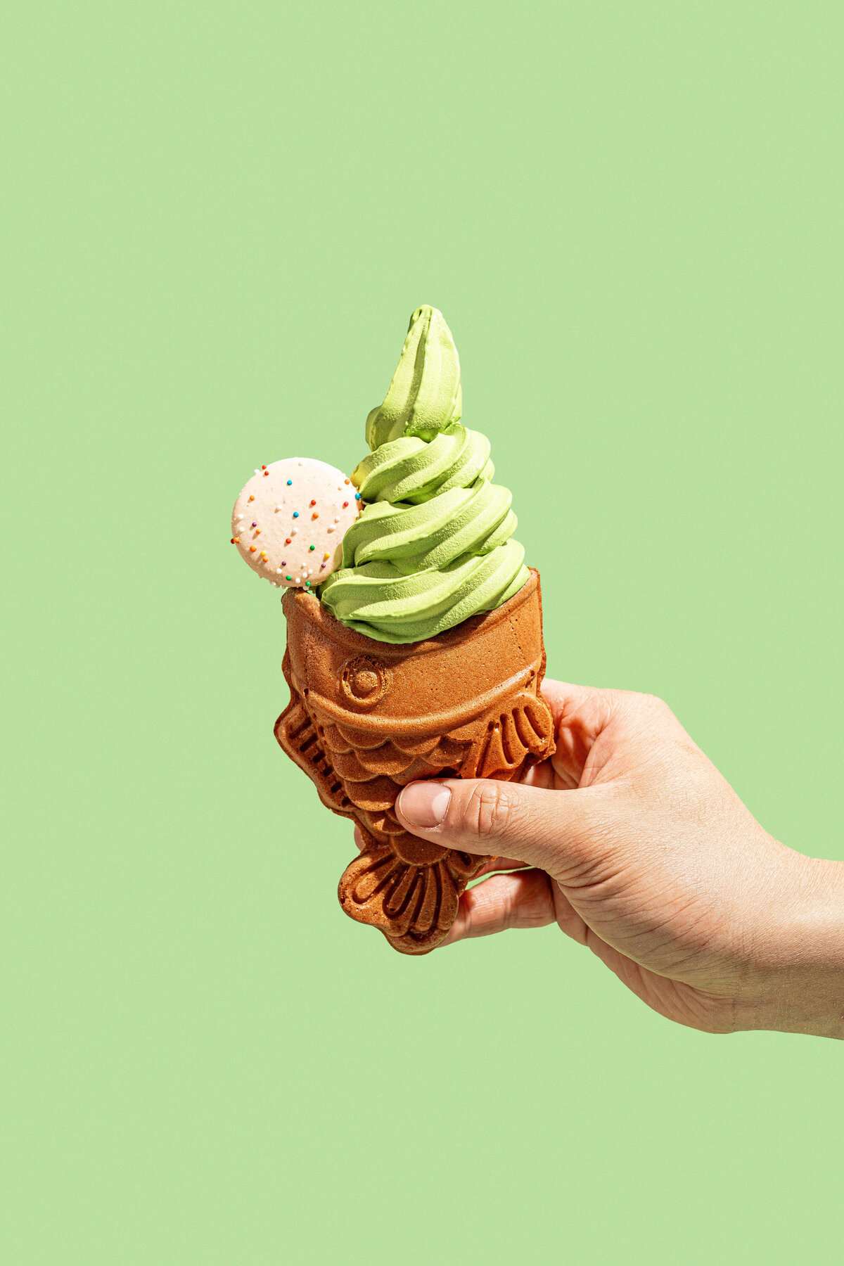 Dessert product photography in Columbia, SC featuring a fish shaped cone with matcha flavored soft serve on a green background
