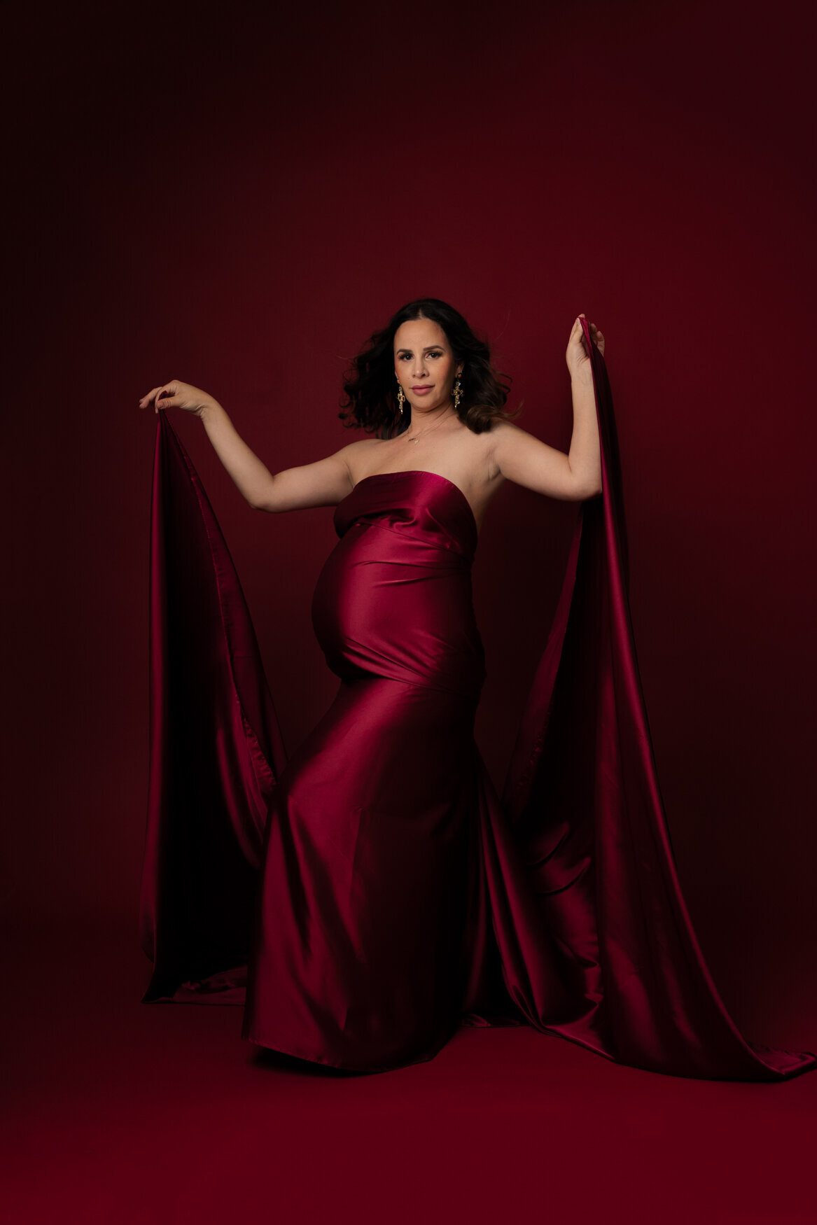 a woman standing with her arms holding a red fabric that covers her body