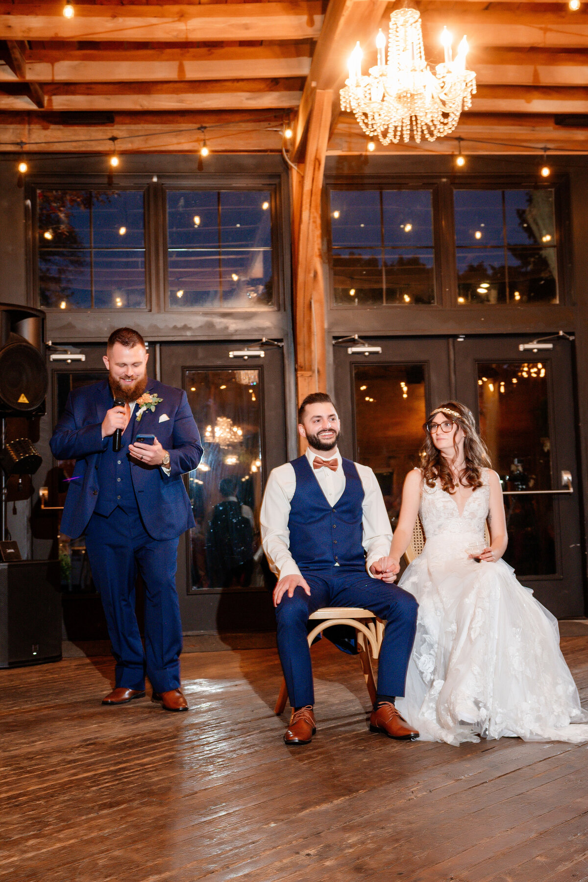 wedding toast in the evening with twinkle lights inside of the barn at shady elms farm
