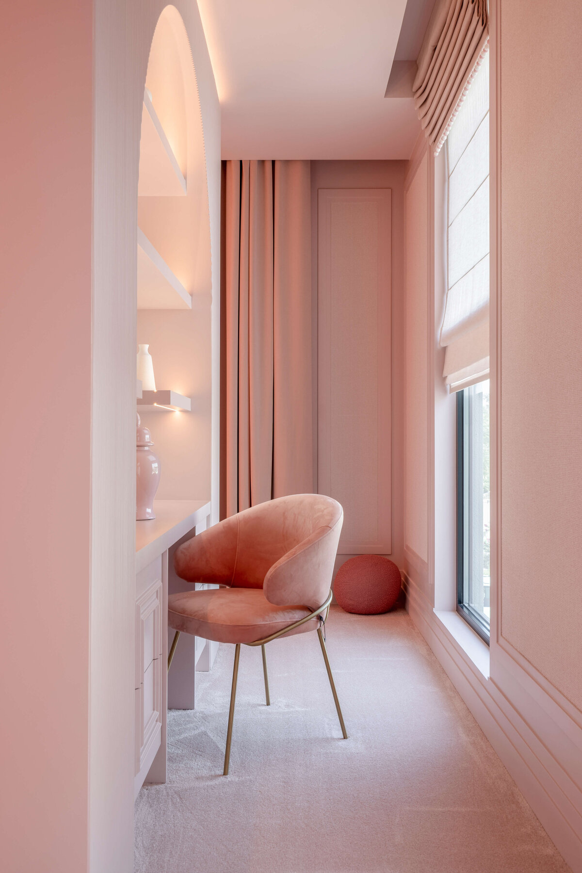 Built in desk in girl's pink bedroom with pink chair.