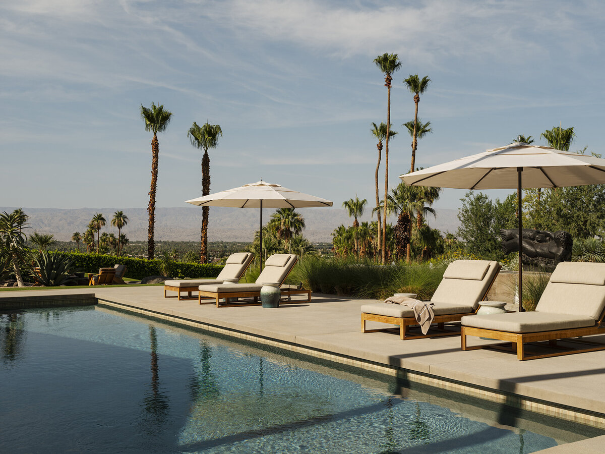 Infinity pool with boulders in landscape and mountain and palm tree views in Palm Springs