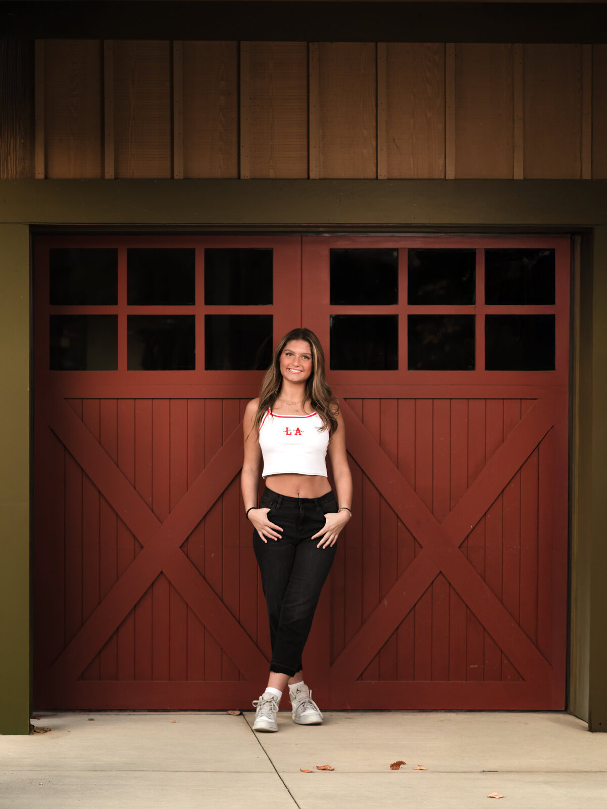 senior girl posing against red barn door for senior photos at Westcreek Reservation in Parma, Ohio