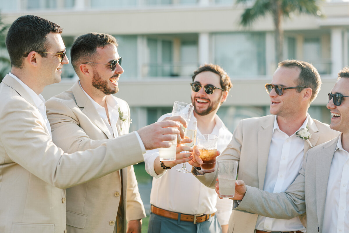 Guests cheer with drinks at a Cancun wedding reception, smiling in the sun, photographed by a Philadelphia wedding pro.