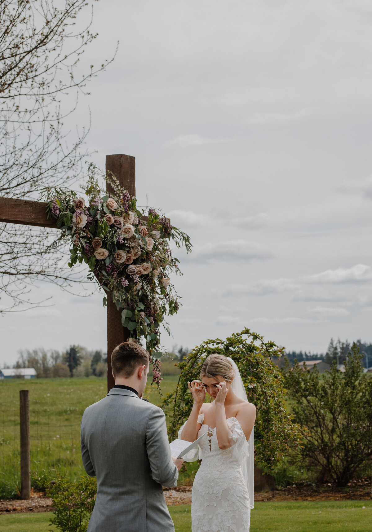 Bride wiping tears while groom reads vows