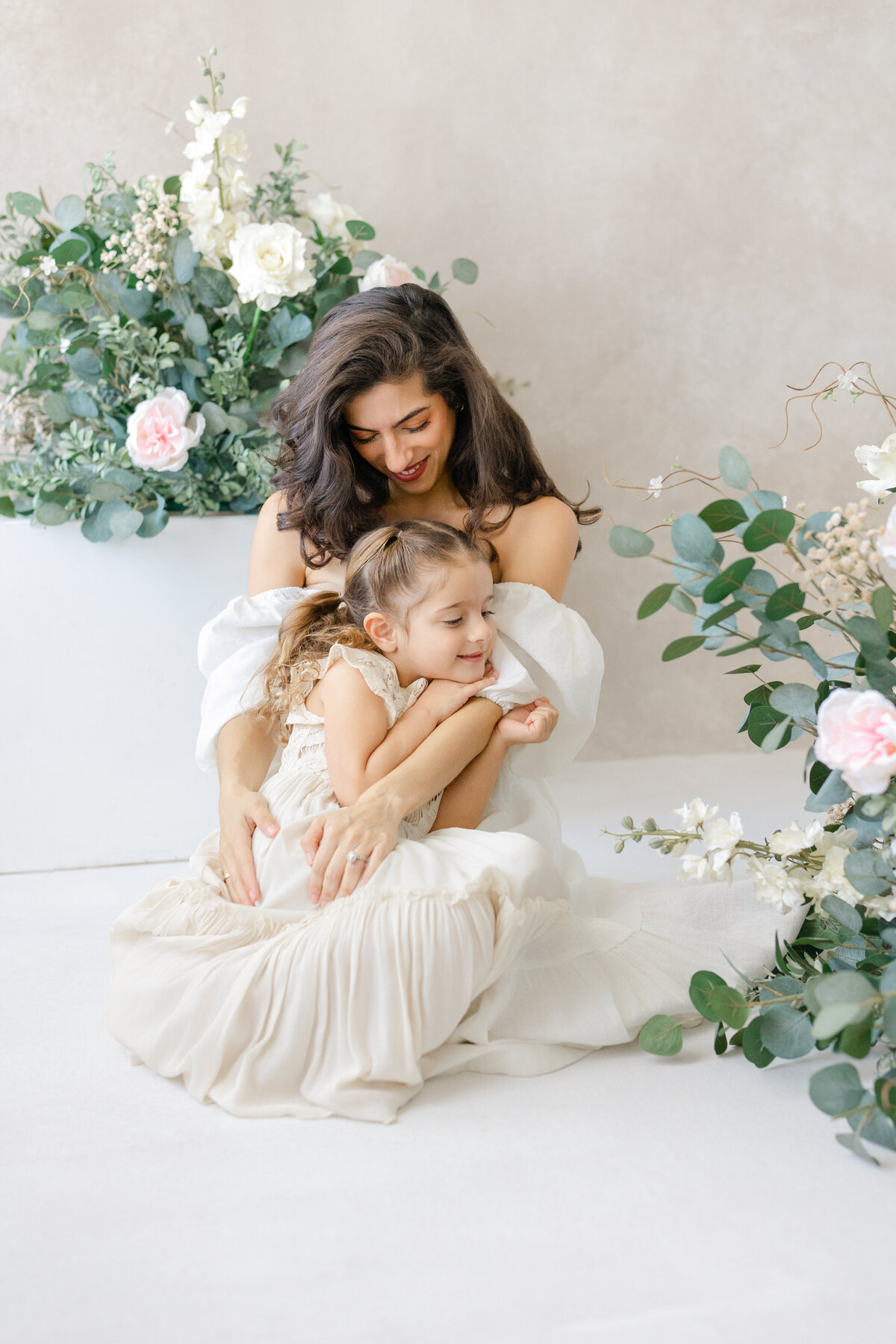 Joyful Tampa motherhood portrait of mom and daughter embracing in soft natural light studio
