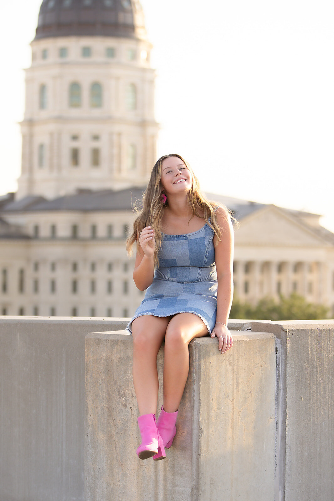 Girl in front of capitol sitting on ledge twirling hair