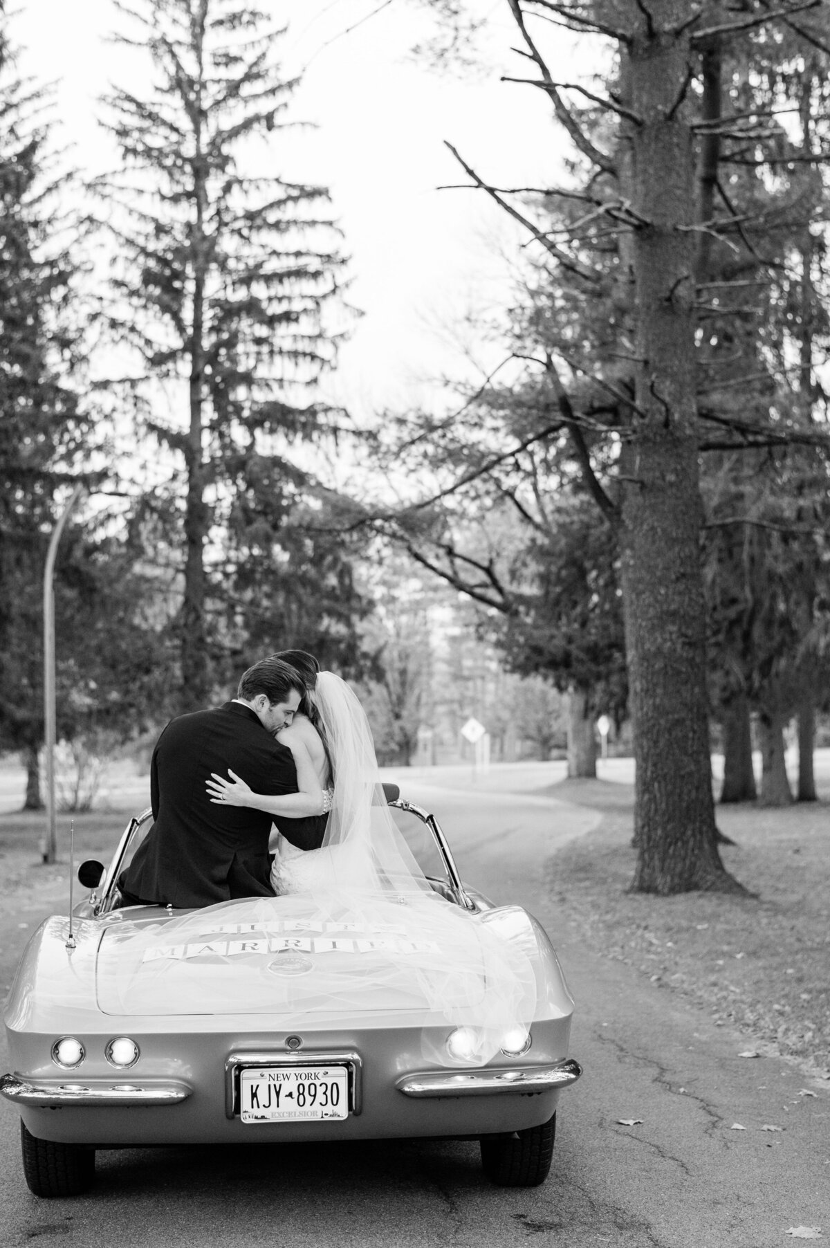 Newlyweds sit on top of their wedding convertible 