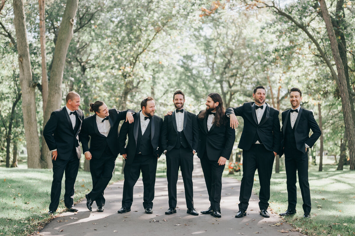 Candid of groom and groomsmen having great time during wedding portraits