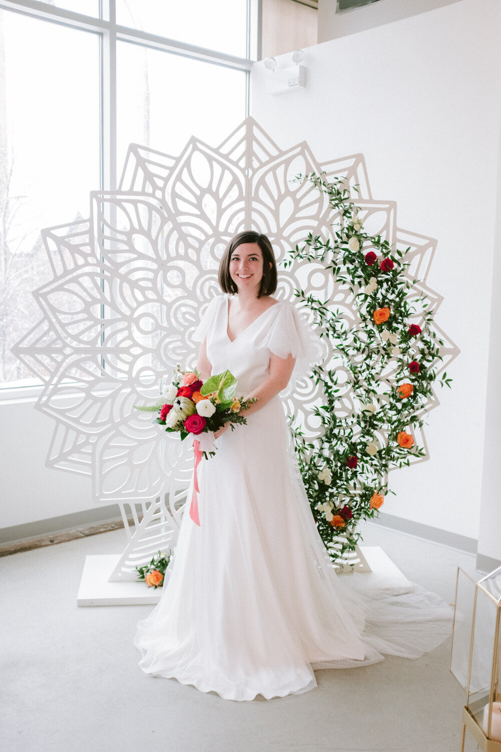 Pretty bride holding her flower bouquet in front of an elegant floral wedding backdrop