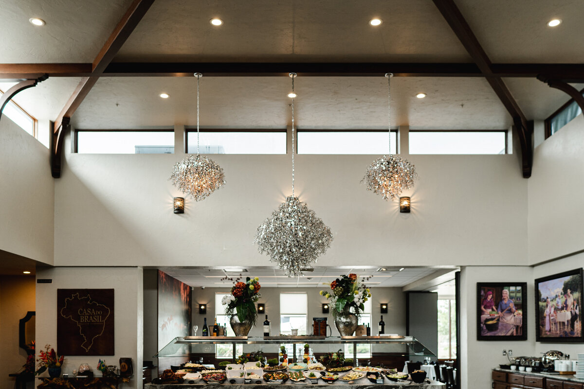 feature ceiling with dark wood beams, clerestory windows and chandeliers above restaurant buffet