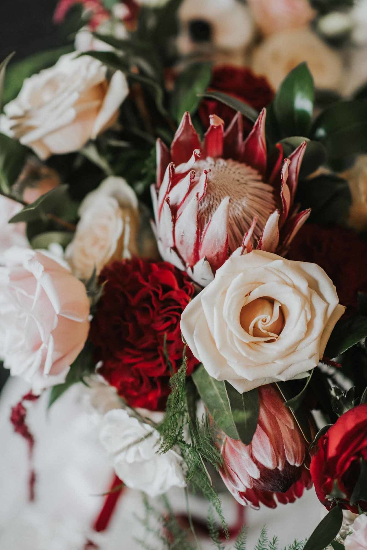 floral detail with pink King protea, red Piano garden roses, Vendella roses, and garden spray roses