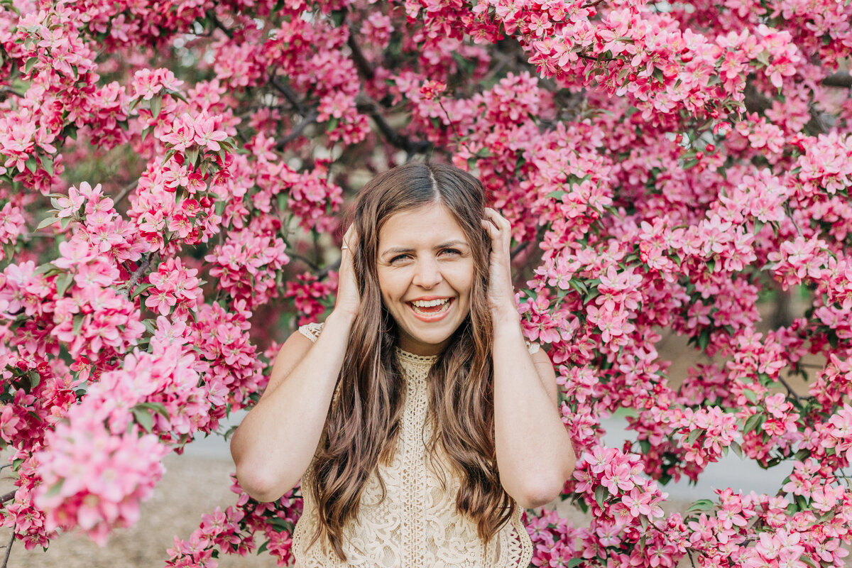 girl standing under flower tree lauging