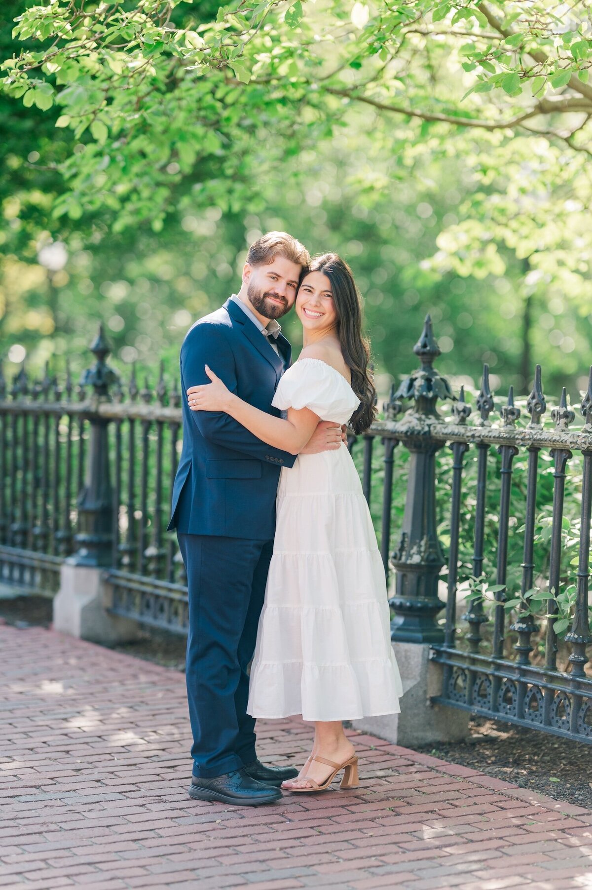 A woman and her fiancé smiling under a tree at Boston public Garden