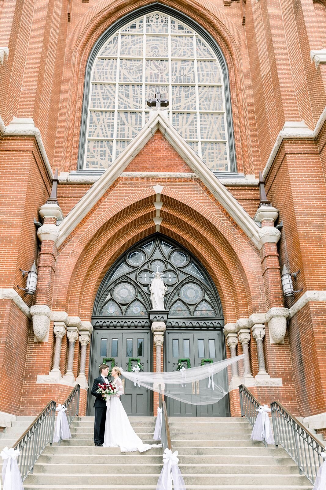 Bride and groom pose on steps of Cathedral of Saint Paul in Birmingham, Alabama