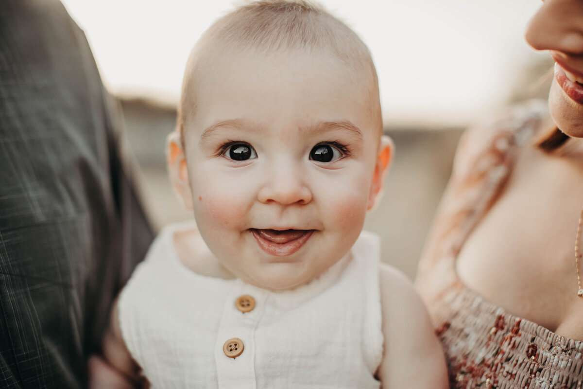 6 month old boy smiling big at the camera. 