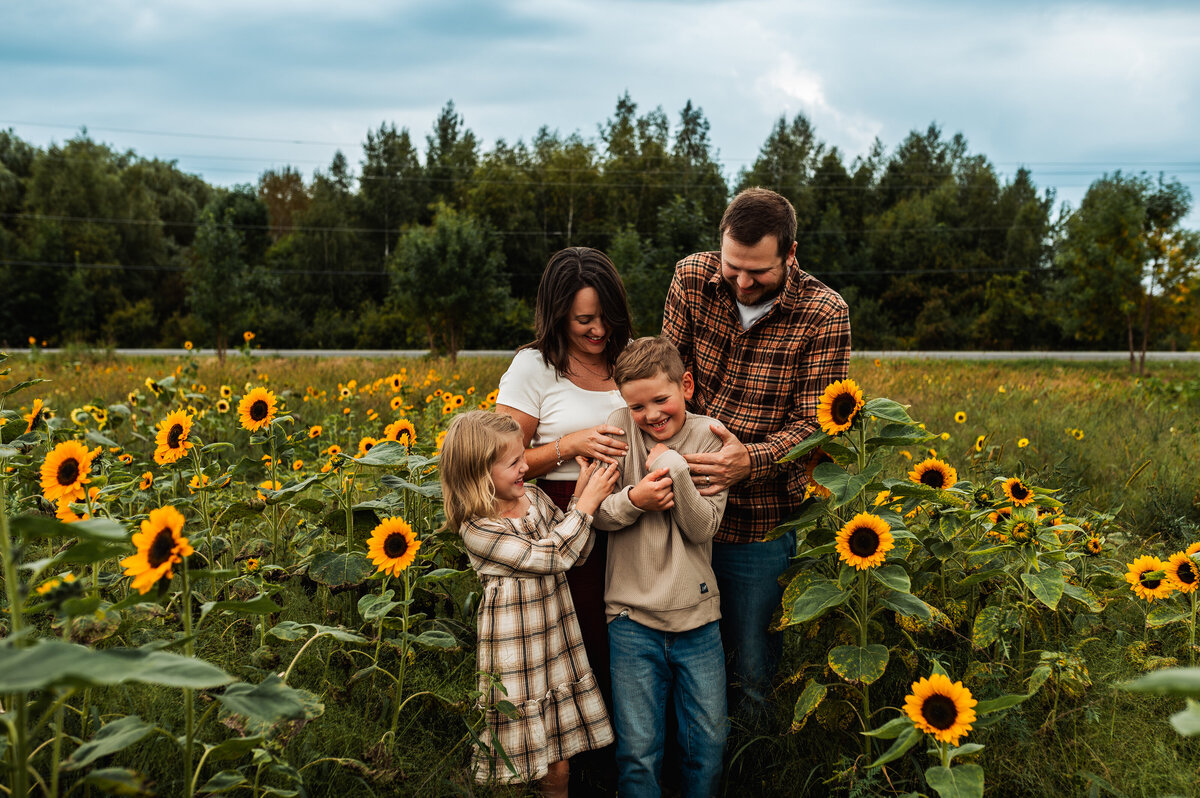 Family of four standing in a sunflower field during Ottawa summer mini session.