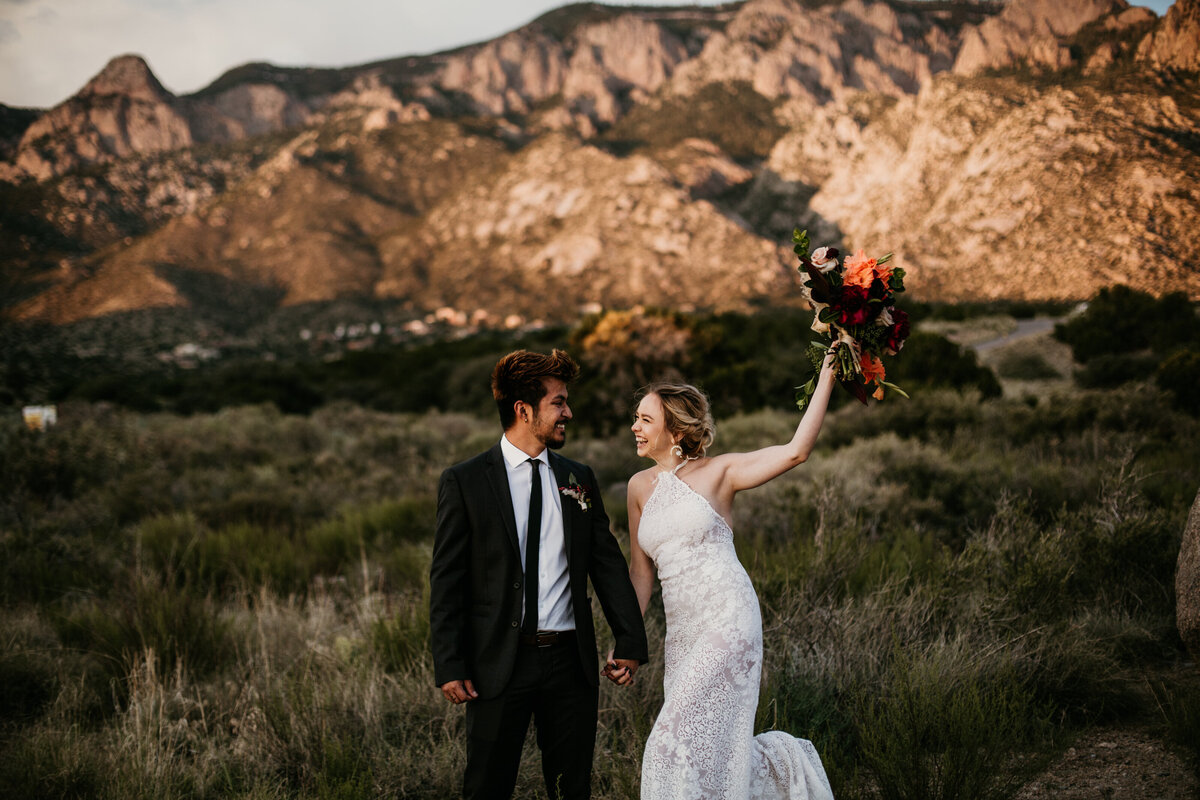 bride and groom jumping in front of a mountain