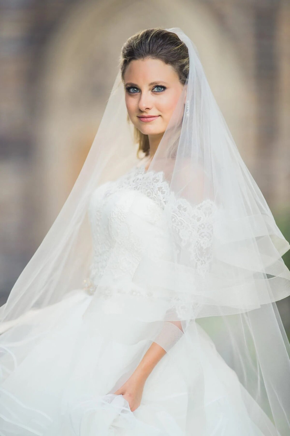 A bride smiling and holding the bottom of her wedding dress