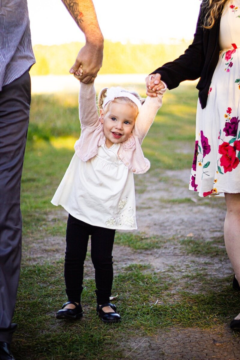 Pregnant mom with her husband and toddler daughter in a field in Edmonton